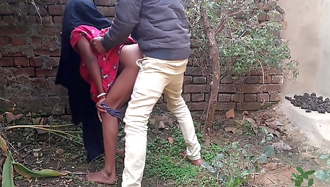 Brunette in a black dress rides a bike on a dirt road